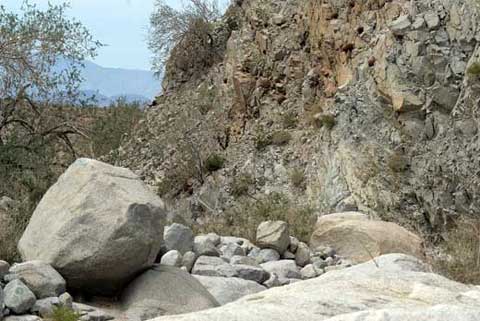 Photo of canyon wall, with fallen boulders in the washj
