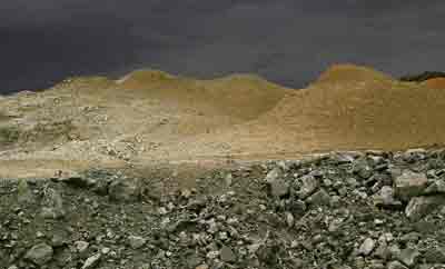 Photo of some mounds containing gypsum and behind them some hills that were mined long ago and have since been restored
